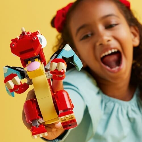 Child excitedly holding a red LEGO dragon